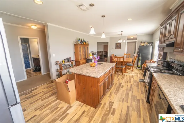 a kitchen with stainless steel appliances granite countertop a refrigerator a stove top oven and a dining table with wooden floor