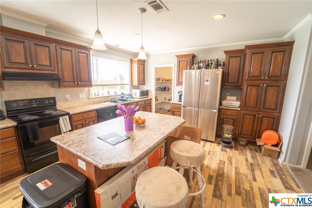 443 Joe Pokluda Road Nordheim, TX 78141 - Photo 18 of 26 a kitchen with stainless steel appliances granite countertop a refrigerator a stove top oven and a dining table with wooden floor