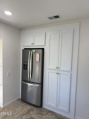 a view of a refrigerator in kitchen and white cabinets
