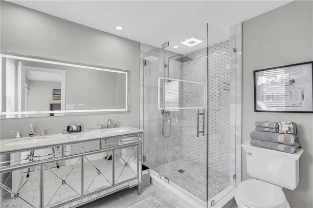a bathroom with a shower sink vanity mirror and toilet