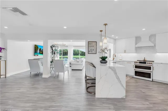 a living room with furniture a flat screen tv and kitchen view