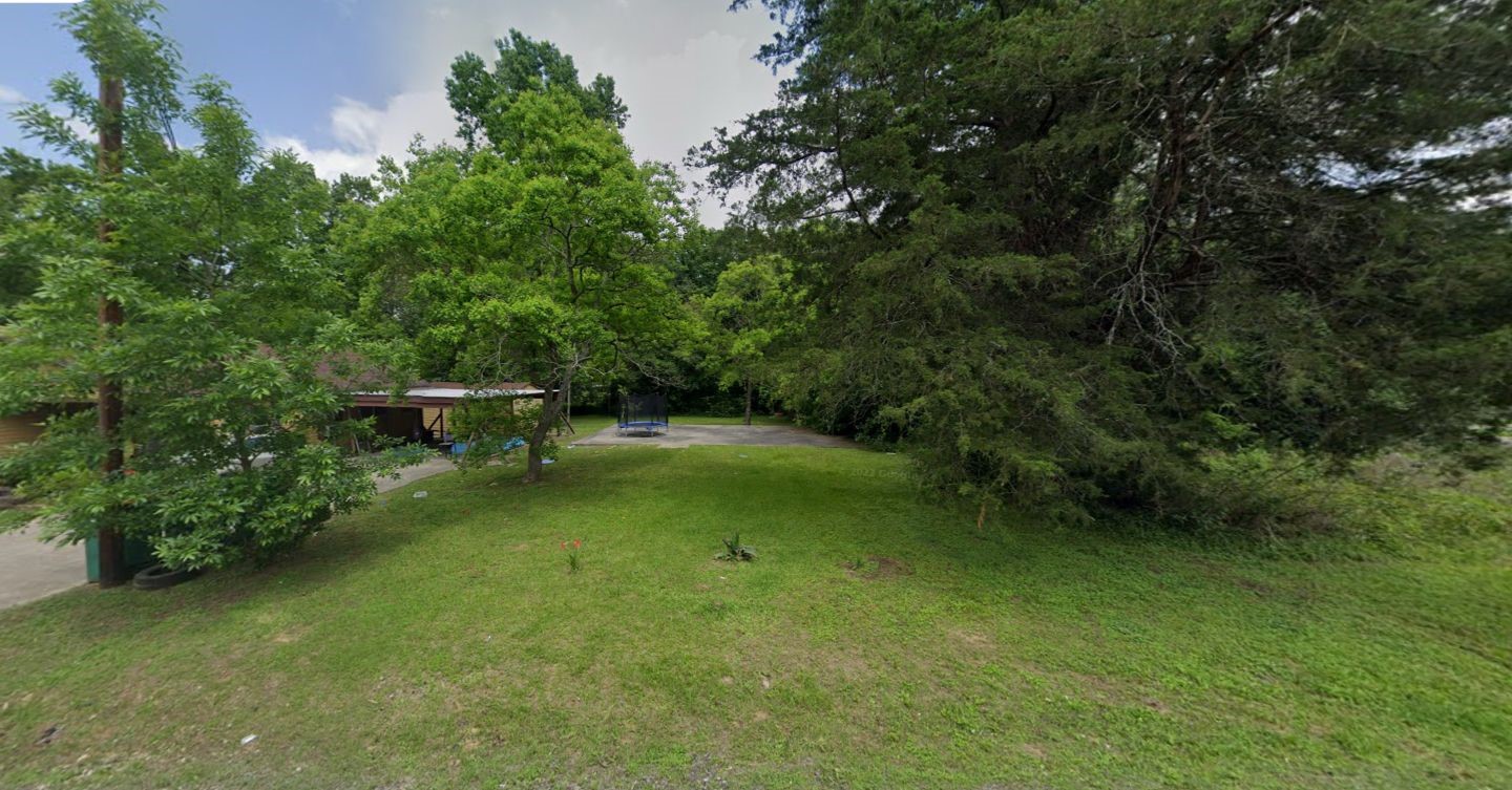 804 North 7th Street Conroe, TX 77301 - Photo 1 of 6 a backyard of a house with lawn chairs plants and large trees