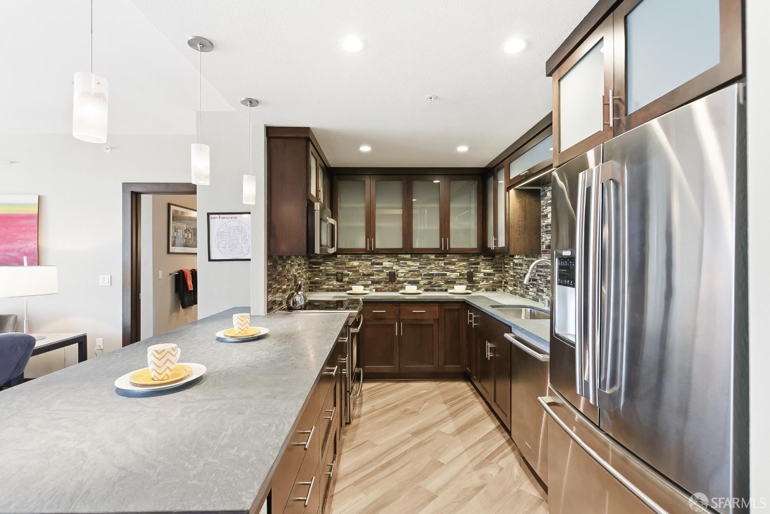 88 King Street, Unit 907 San Francisco, CA 94107 - Photo 3 of 51 custonm remodeled kitchen featuring appliances with stainless steel finishes, pendant lighting, glass insert cabinets, tiled backsplash, granite countertops and light tiled finished floors