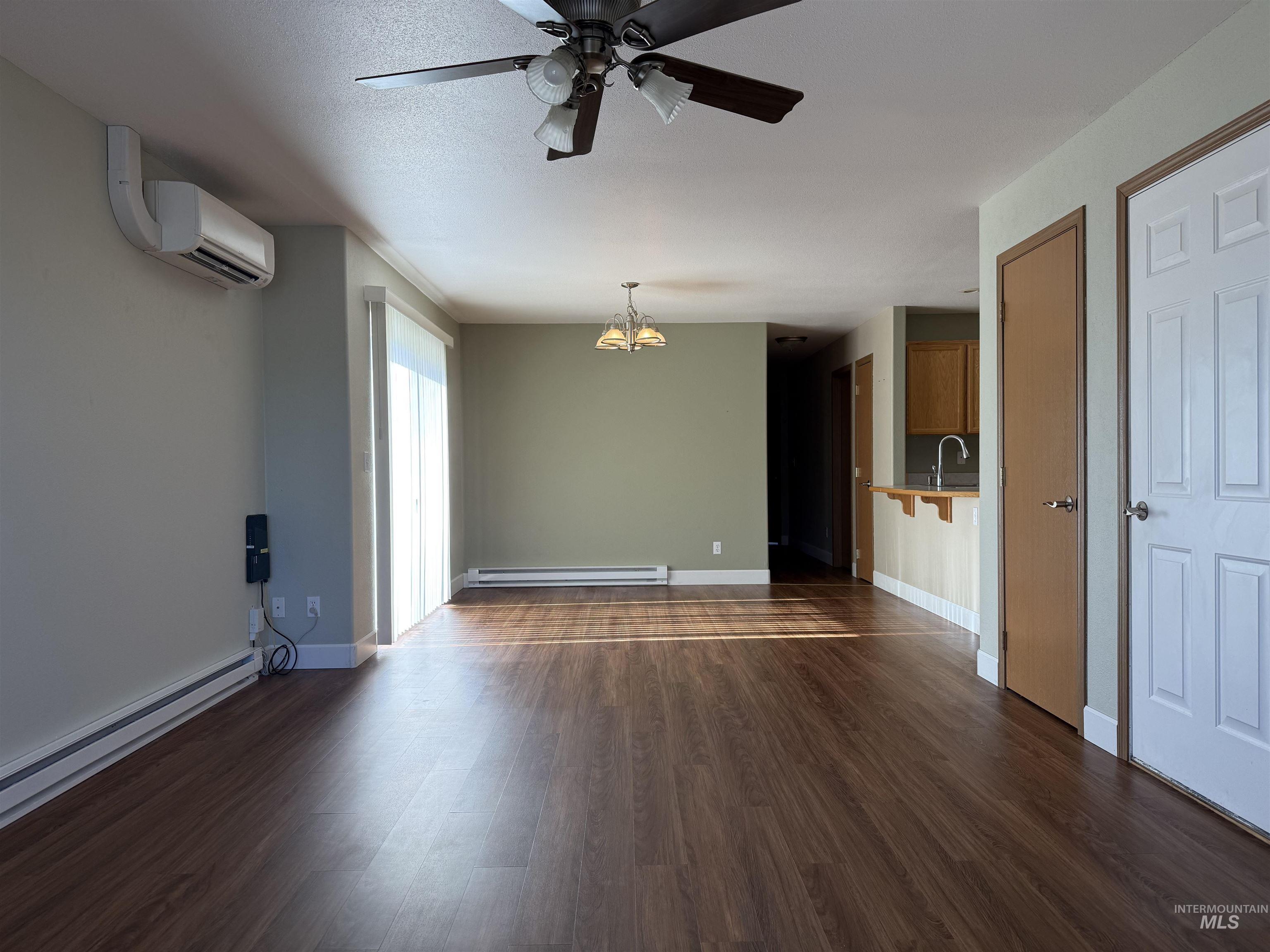 257 Pintail Lane Moscow, ID 83843 - Photo 2 of 28 Unfurnished living room featuring ceiling fan, dark wood finished floors, suspended lighting, and baseboard heating