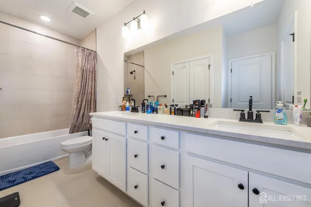 a bathroom with a double vanity sink toilet and a mirror