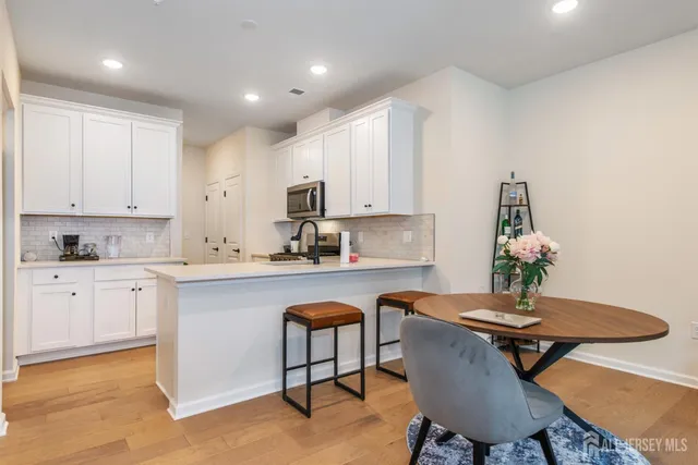 a kitchen with granite countertop white cabinets a table and chairs in it