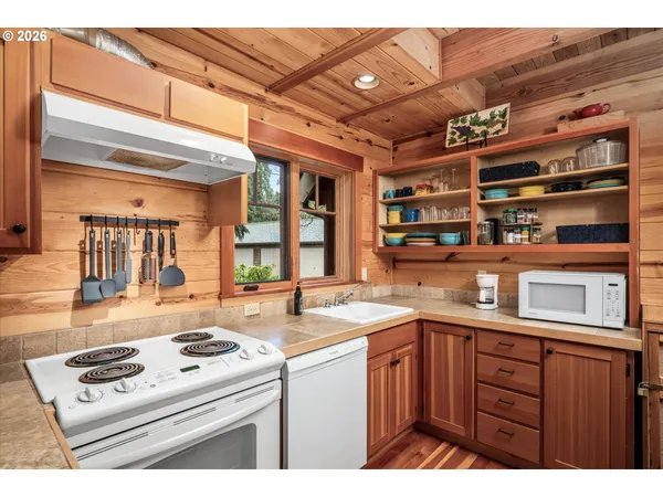 a kitchen that has a sink a stove and wooden cabinets