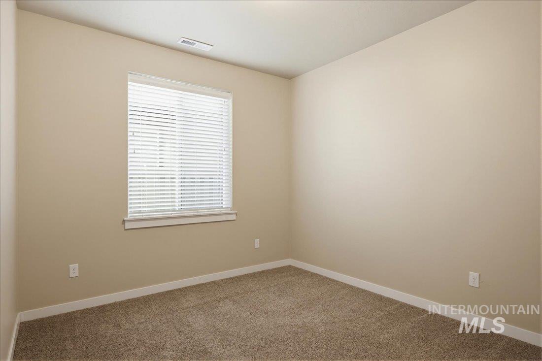 12460 West Azure Street Boise, ID 83713 - Photo 25 of 34 Neutral-toned wall finishes featuring a prominent window with horizontal blinds, tan carpeting, and white baseboards