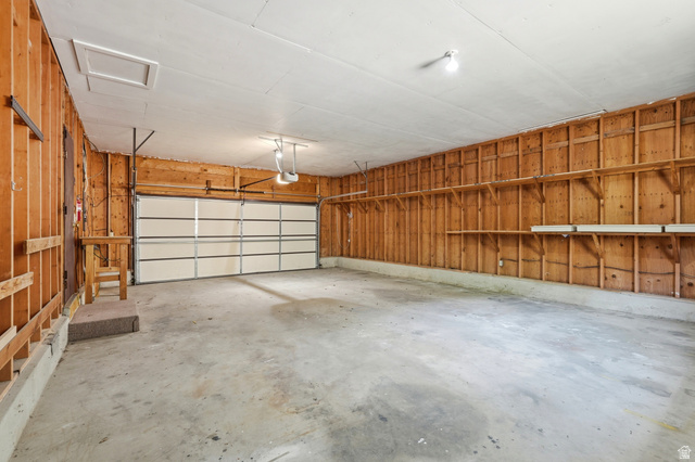 1410 Sumac Drive Logan, UT 84321 - Photo 11 of 28 Spacious two-car garage featuring a sectional garage door, concrete flooring, exposed wood stud walls, and built-in shelving units