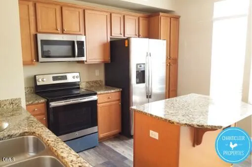 a kitchen with granite countertop a refrigerator stove and microwave