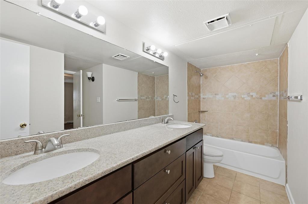 4526 Carr Street The Colony, TX 75056 - Photo 13 of 19 a bathroom with a granite countertop sink a toilet a mirror a bathtub and shower