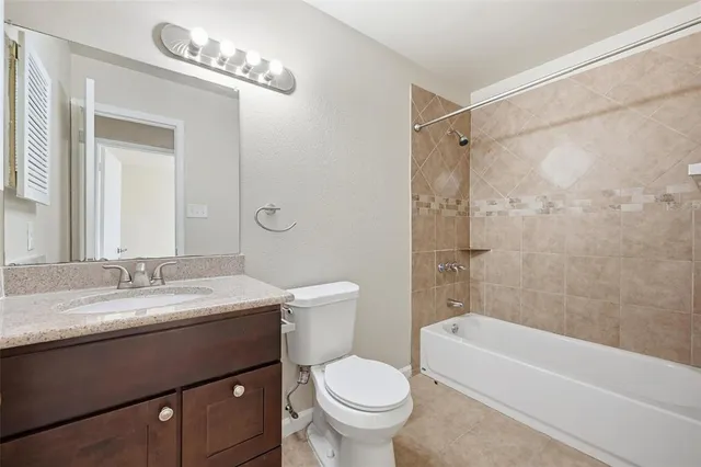 a bathroom with a granite countertop sink a toilet a mirror a bathtub and shower