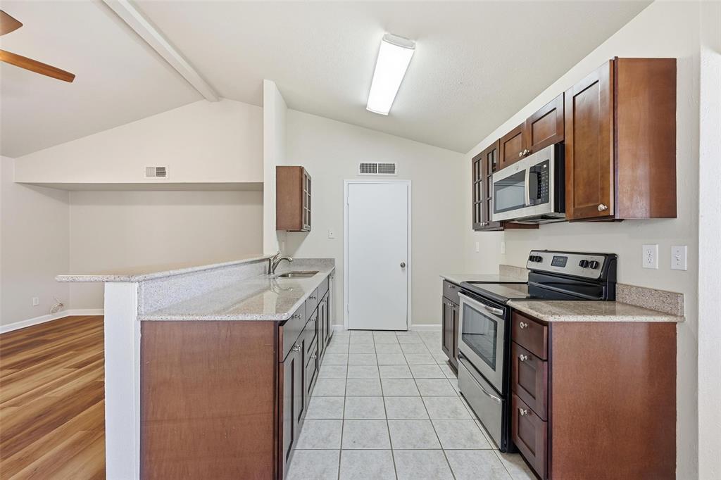 4526 Carr Street The Colony, TX 75056 - Photo 4 of 19 a kitchen with stainless steel appliances granite countertop a stove a sink and a microwave
