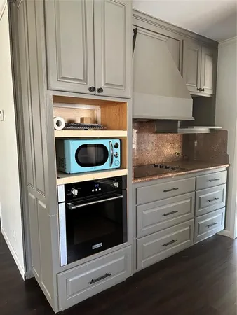 a kitchen with granite countertop white cabinets and a stove with wooden floor