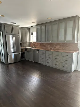 a kitchen with stainless steel appliances a refrigerator a sink a stove a microwave and wooden floors