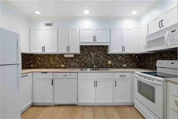 a kitchen with white cabinets stainless steel appliances and sink