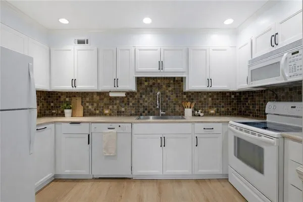 a kitchen with white cabinets granite counter tops and a stove