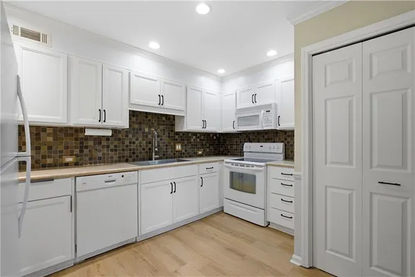 a kitchen with white cabinets stainless steel appliances and sink