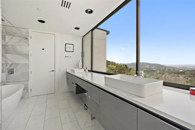 a large white kitchen with a sink and dishwasher with a large window