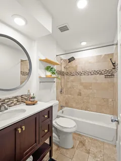 a bathroom with a bathtub shower sink vanity mirror and toilet
