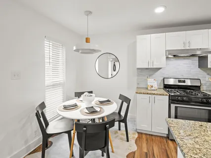 a kitchen with stainless steel appliances granite countertop a stove a sink a dining table and chairs with wooden floor