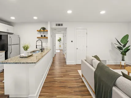 a living room with stainless steel appliances furniture a rug and a kitchen view