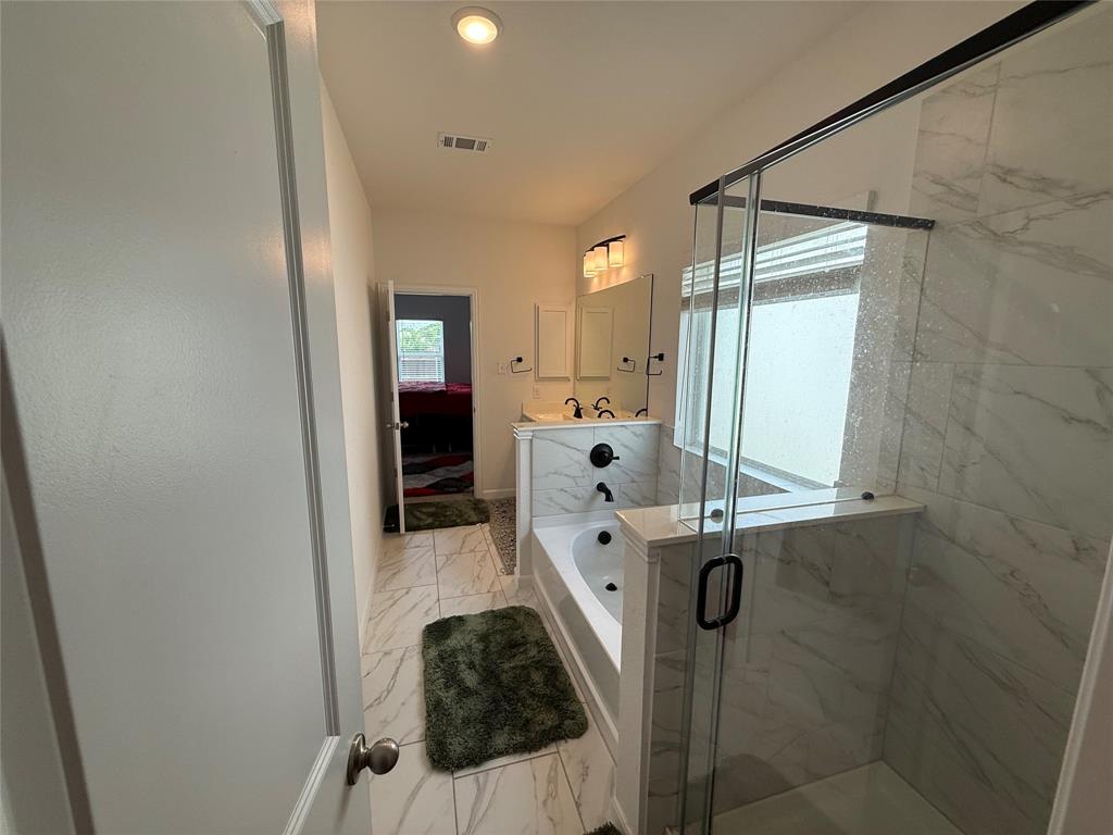 2006 Placerville Street Forney, TX 75126 - Photo 20 of 35 Bathroom featuring a glass-enclosed shower with marble-look tile, a separate built-in soaking tub, dual vanity with undermount sinks, and marble-look tile flooring