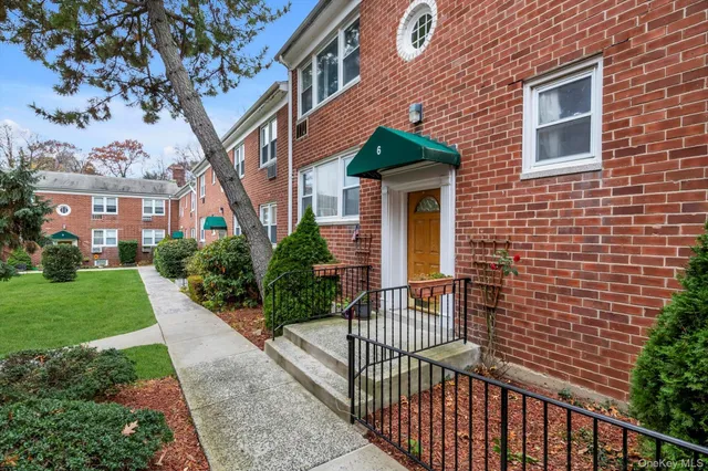 a view of a brick house with a yard and large trees