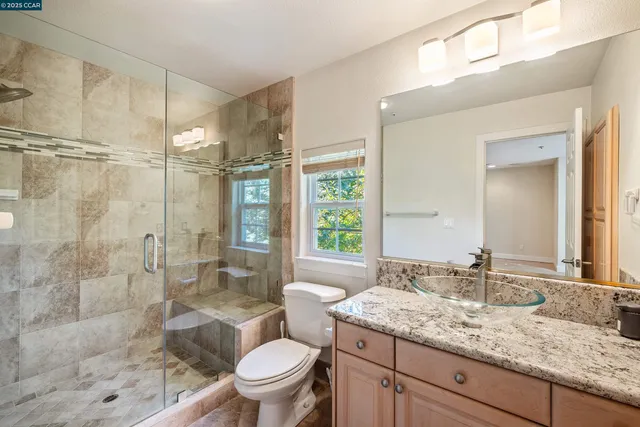 a bathroom with a granite countertop sink toilet and shower