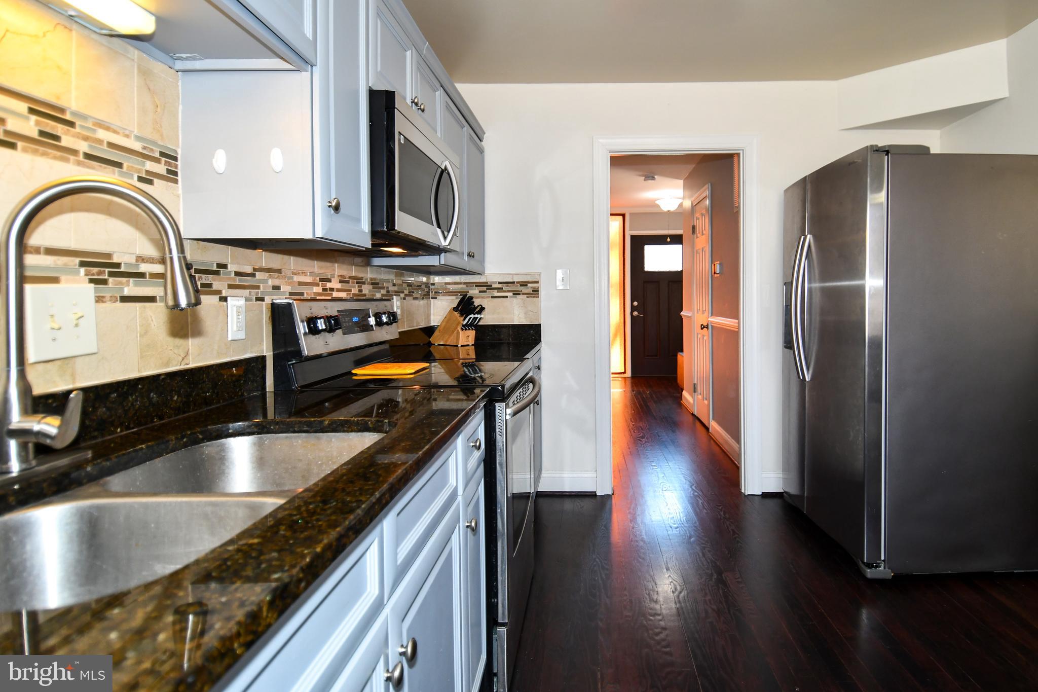 12604 Dulcinea Place Woodbridge, VA 22192 - Photo 26 of 63 a kitchen with stainless steel appliances granite countertop a sink a refrigerator and wooden cabinets