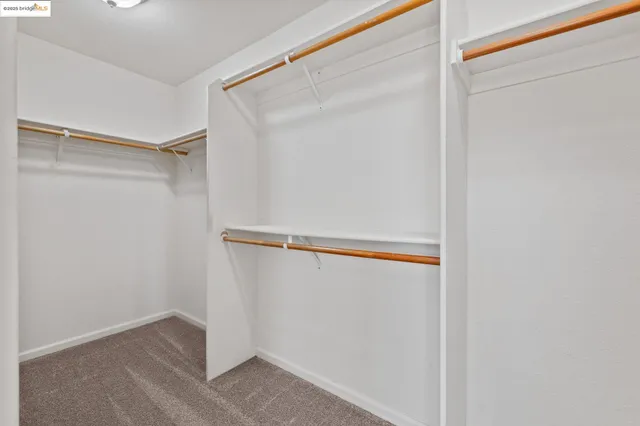 an empty room with chandelier fan and windows