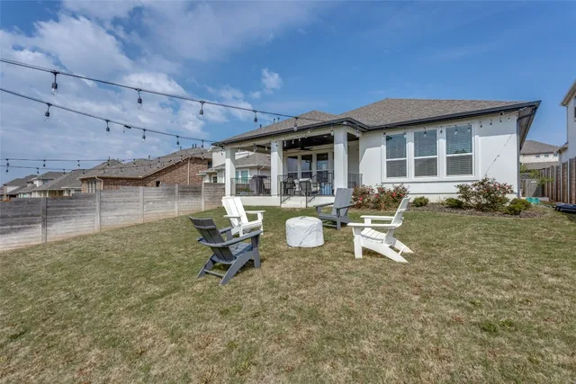 a view of a backyard with chairs and potted plants