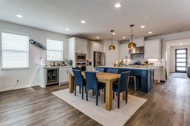 a open kitchen with kitchen island a dining table chairs and white cabinets