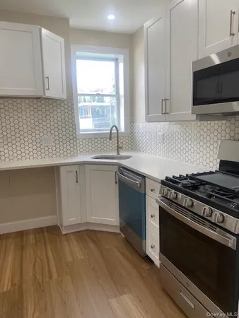 a kitchen with granite countertop a stove a sink and a microwave