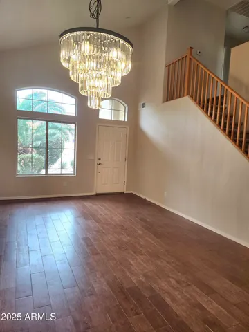an empty room with wooden floor chandelier and windows