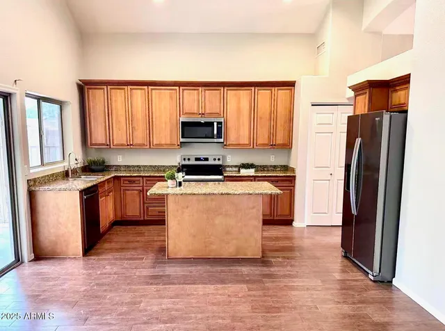 a kitchen with granite countertop a refrigerator stove top oven and sink