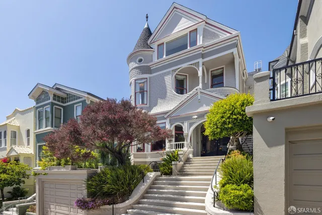 a front view of a multi story residential apartment building with yard and parking