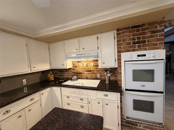 a kitchen with granite countertop white cabinets and white appliances