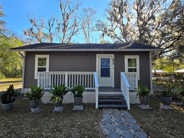 a front view of a house with porch and chairs