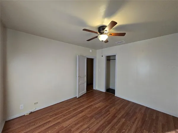 a view of a big room with wooden floor and a chandelier fan