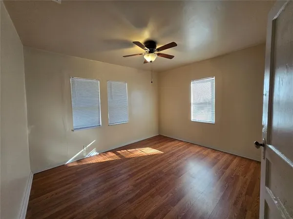 a view of an empty room with window and wooden floor