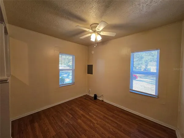 a view of empty room with wooden floor and fan