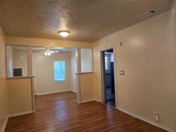 a view of an empty room with wooden floor and a window