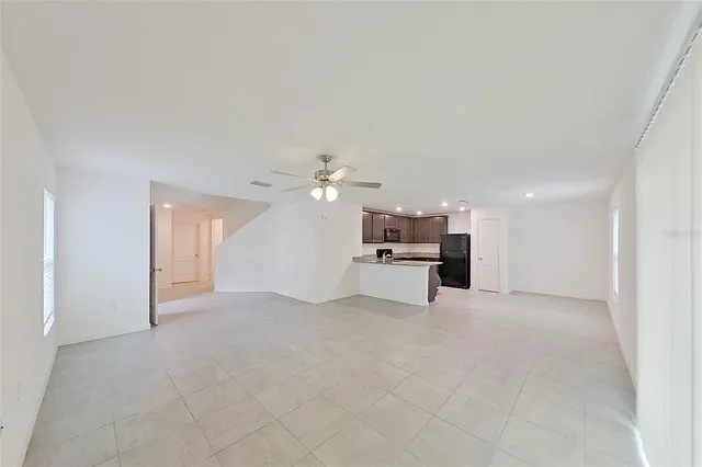 an empty room with fireplace and chandelier fan