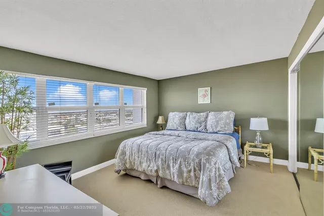 a bedroom with a bed lamp and a large window