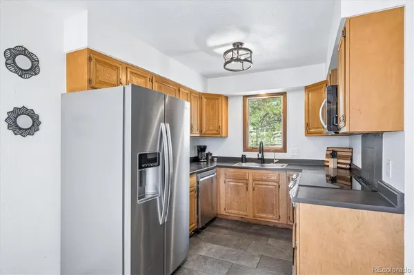 a kitchen with stainless steel appliances granite countertop a sink a stove cabinets and a window