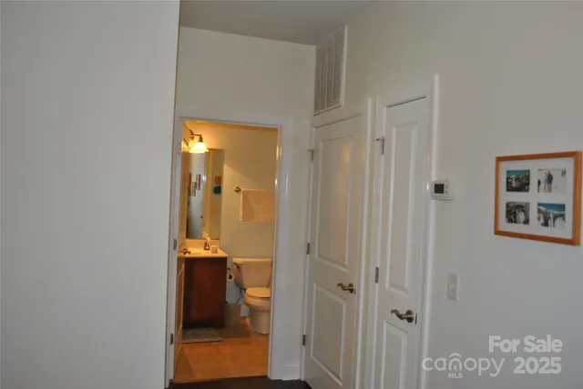 a view of a hallway with wooden floor and a bathroom