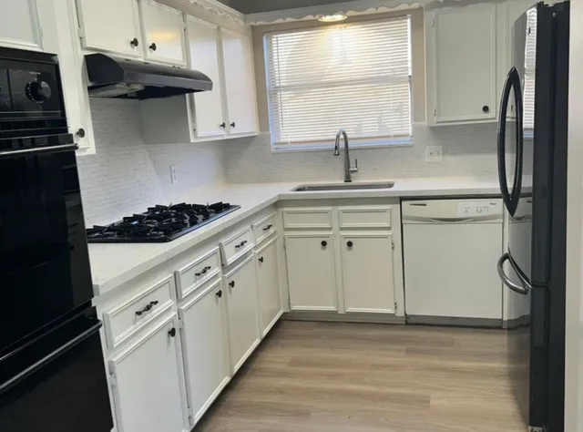 a kitchen with stainless steel appliances white cabinets a stove a sink and a window