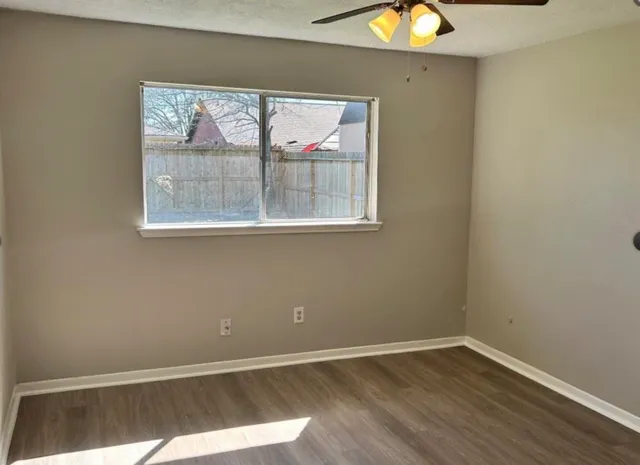 an empty room with a window and wooden floor