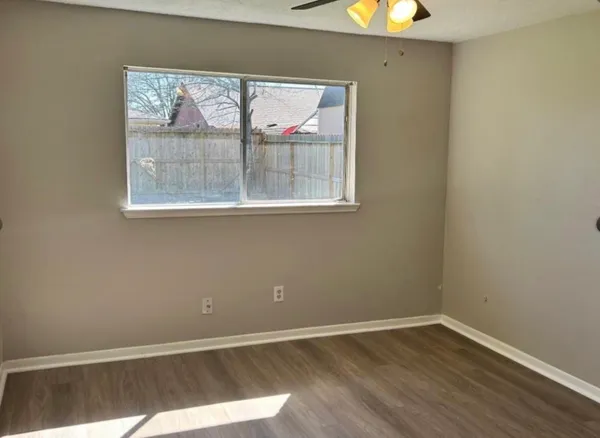 an empty room with wooden floor and windows